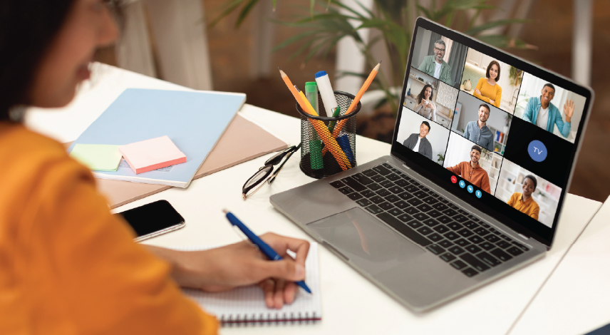 Woman sitting at a desk with her laptop open to a video call with multiple participants.