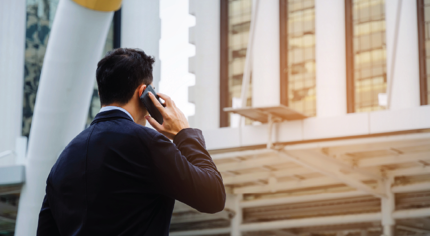 Man in a suit talking on his phone outside.