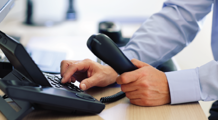 Close-up of a hand dialing numbers on a telephone keypad.