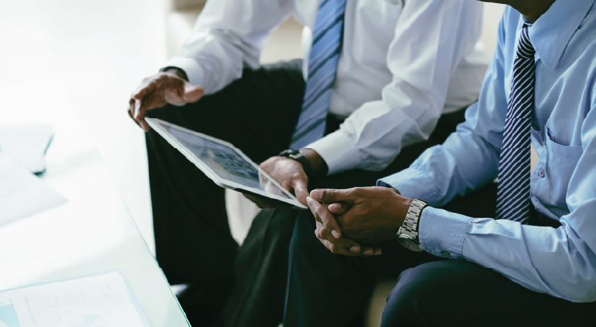 Cropped image of business partners discussing information on tablet computer.