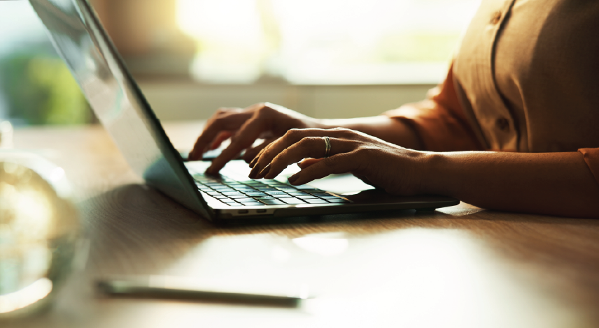 Close-up of a woman typing on her laptop.