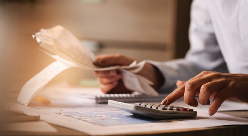 Close-up of a man using calculator while going through bills.